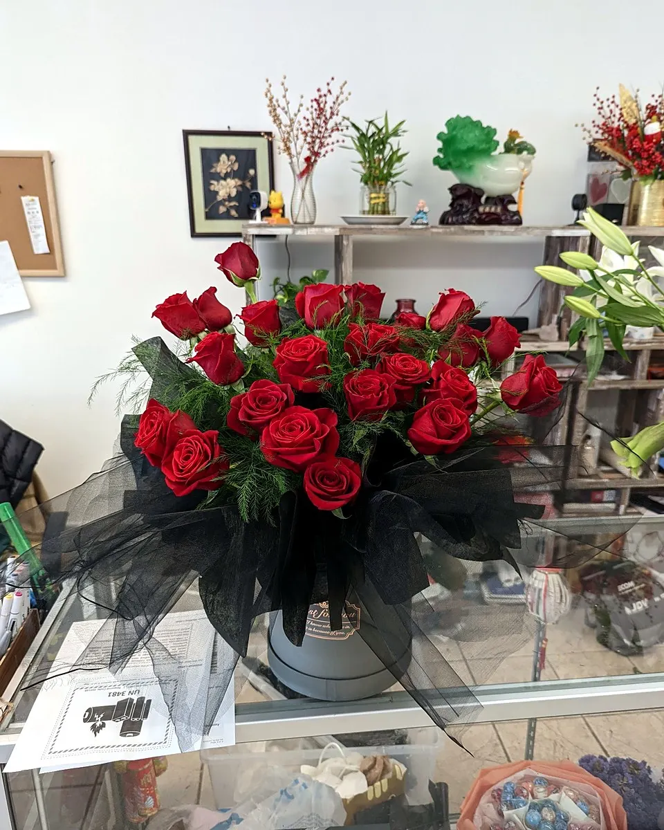 Hand-tied bouquet of red roses, white blooms, and dark foliage