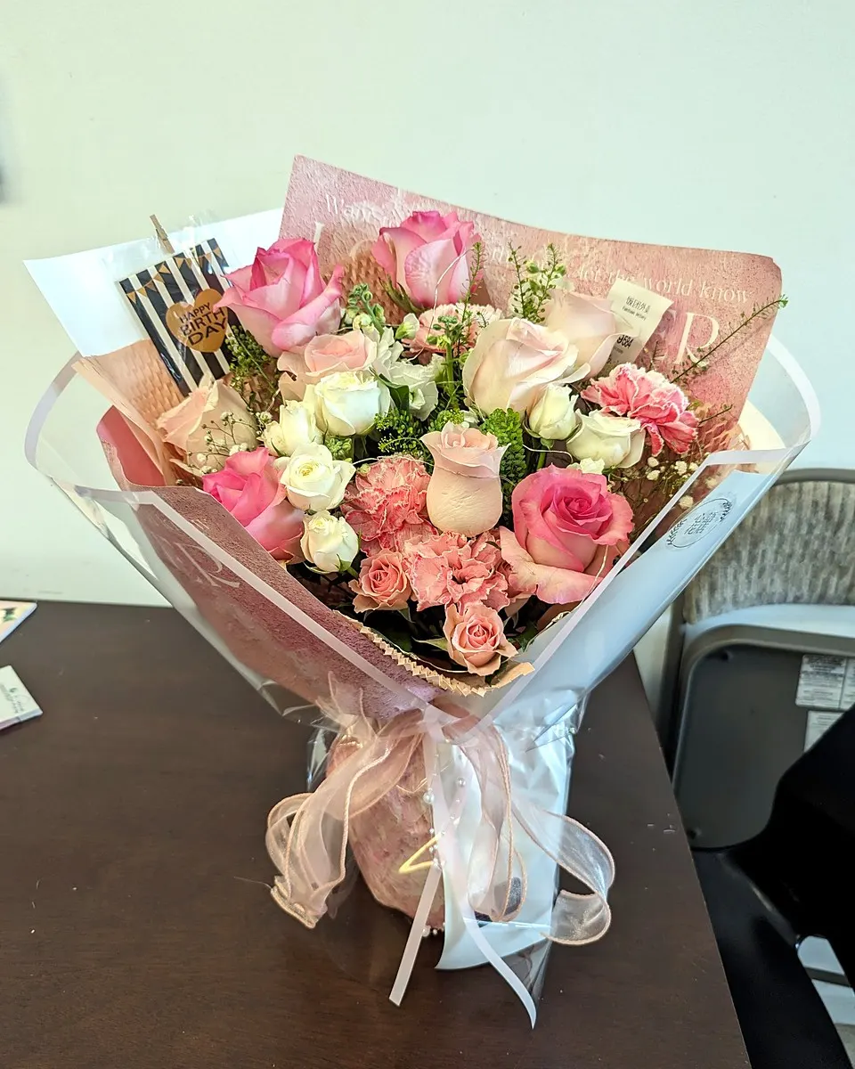 Coral and blush rose bouquet wrapped in white paper