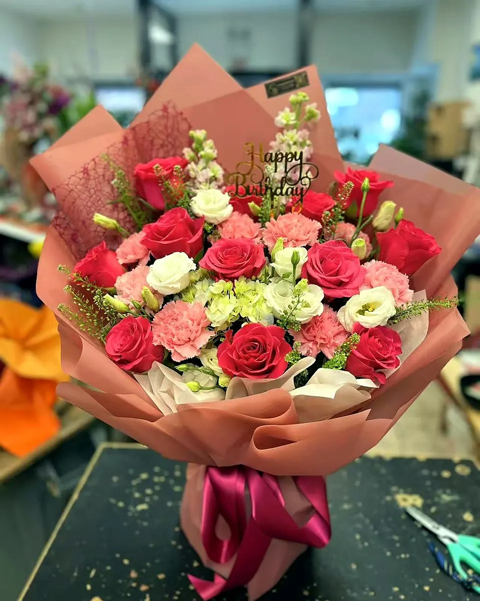 Red and golden bouquet with roses, lilies, and decorative accents