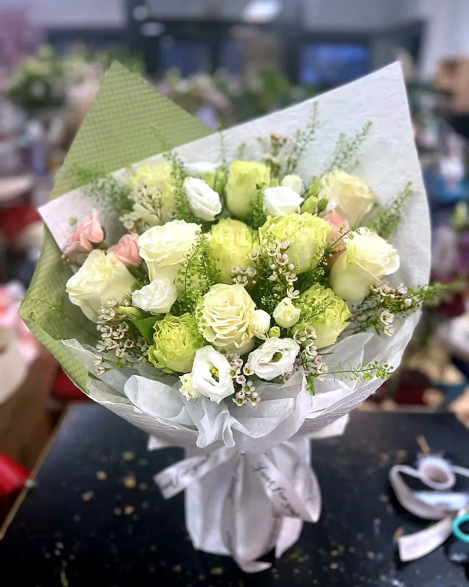 Ivory rose bouquet with pale green blooms and white wrapping