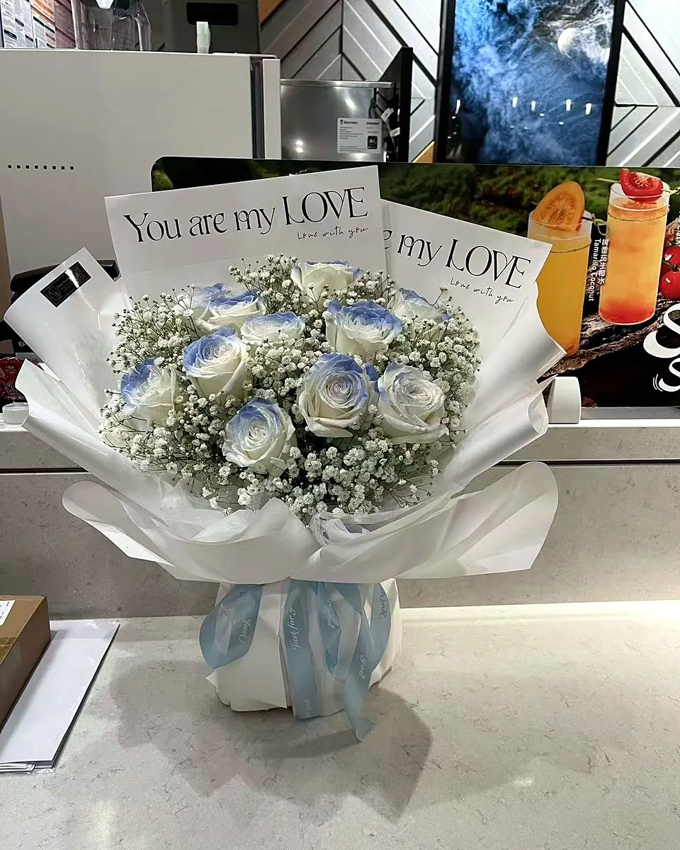 White and pale lilac bouquet arranged in soft blue wrapping