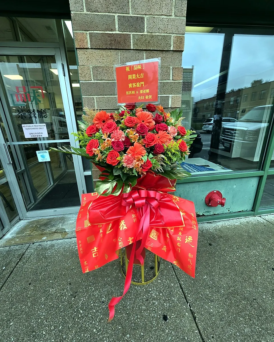 Red grand opening flower stand displayed in front of a storefront
