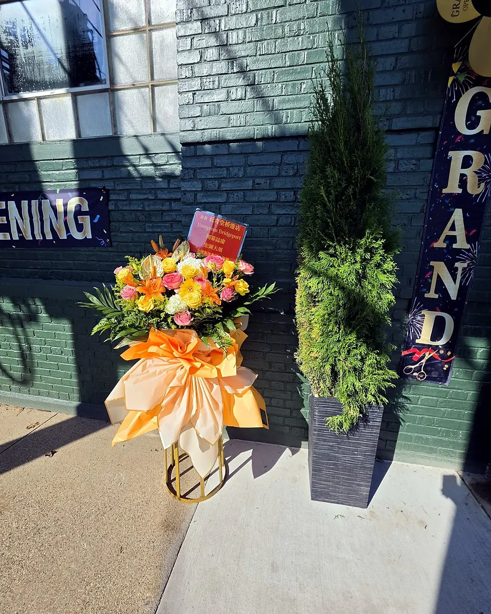 Orange and warm-toned grand opening flower arrangement on a standing frame