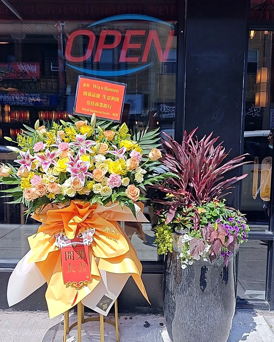 White and yellow grand opening flower stand displayed outside a business