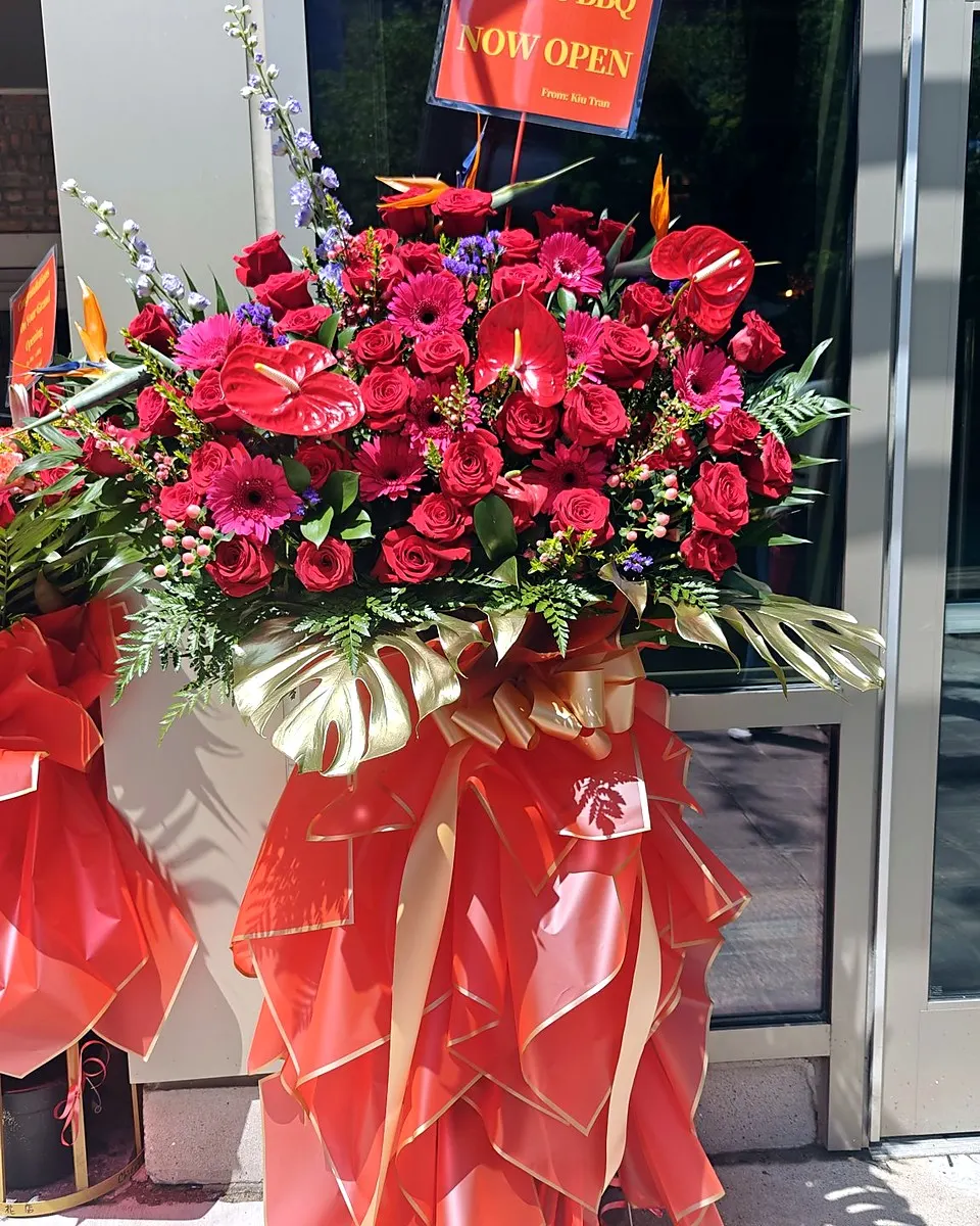 Bright red grand opening flower stand with a matching ribbon bow