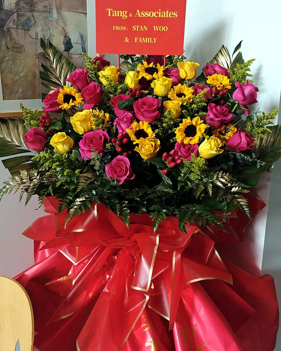 Red and orange grand opening flower stand with lilies, roses, and gerbera daisies