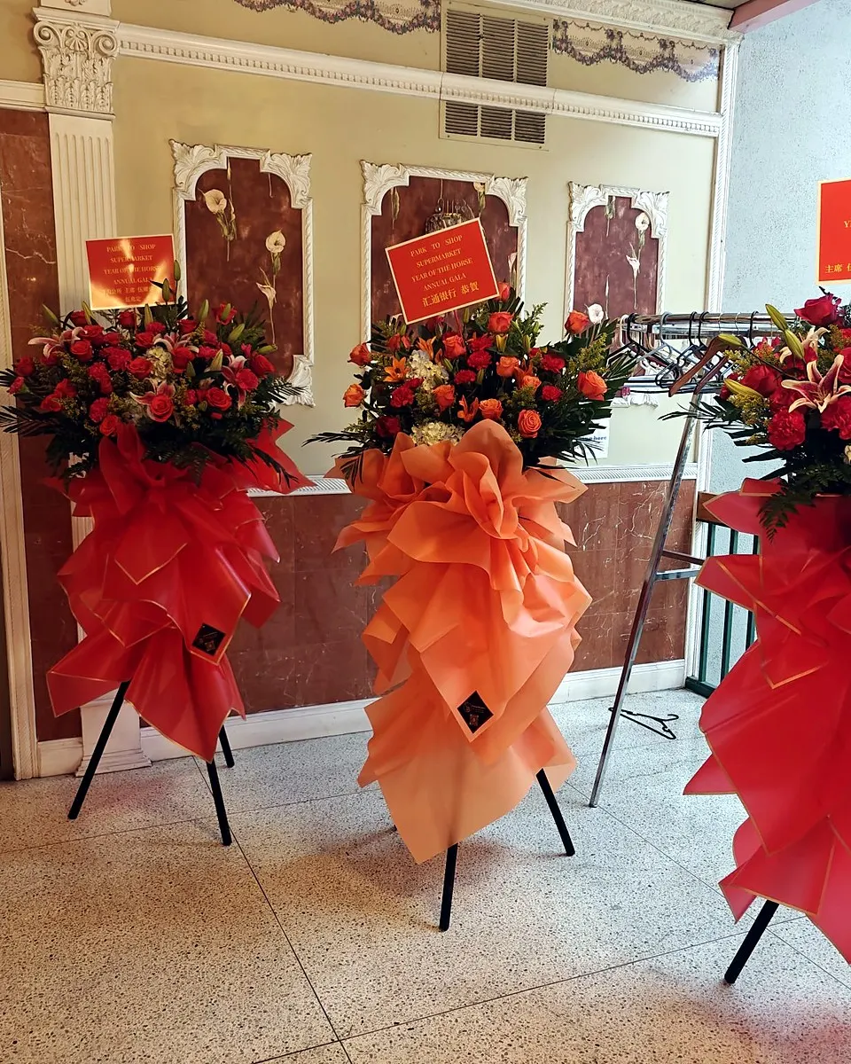 Three red and orange grand opening flower stands at a banquet venue