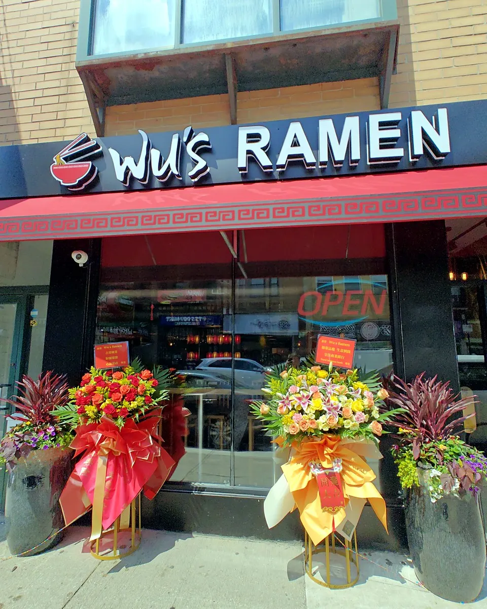 Red and orange grand opening flower stand wrapped with black and gold ribbons
