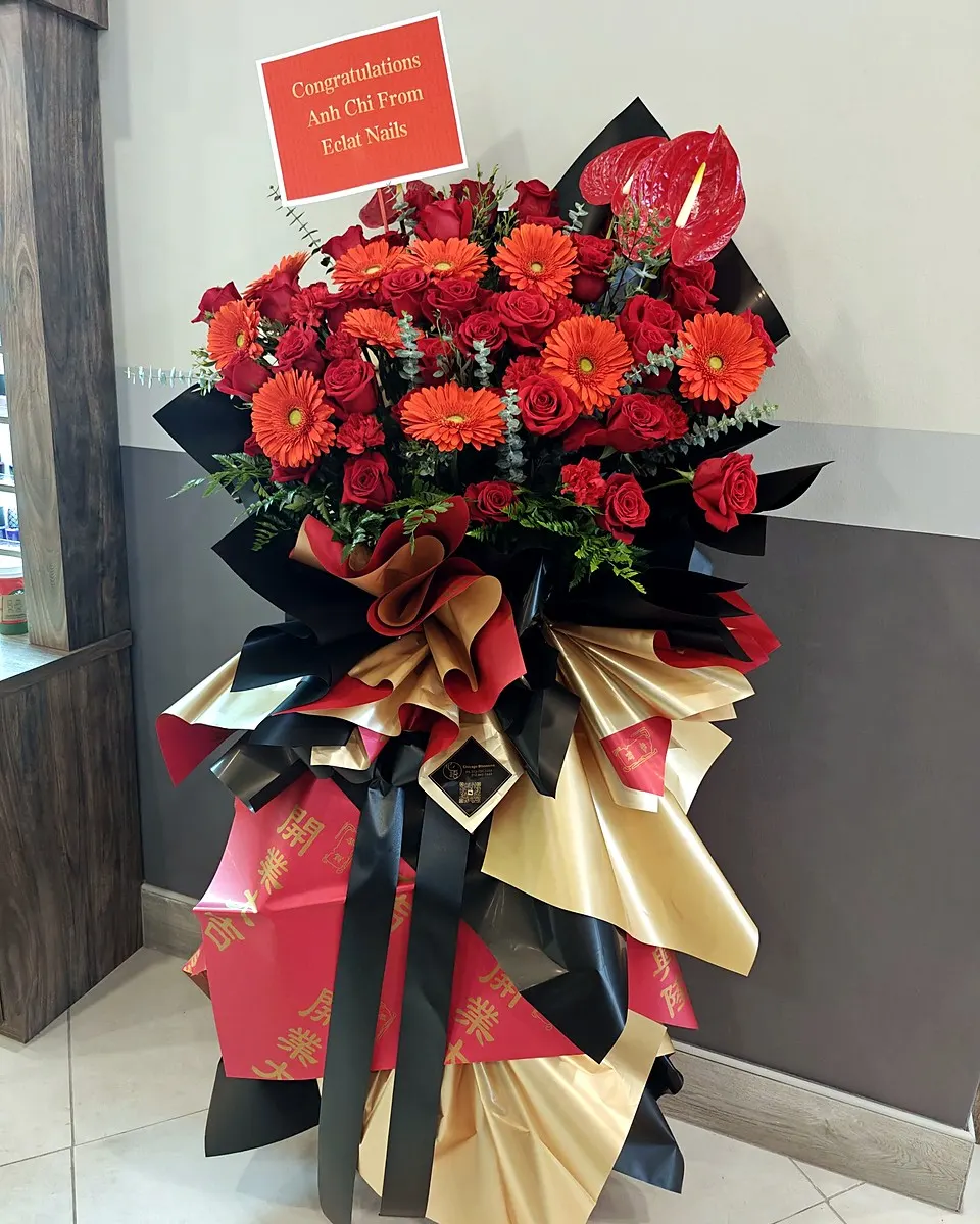 Two-tier red and pink grand opening floral arrangement with gold and red wrapping