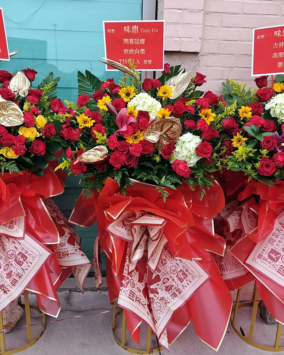Three red grand opening flower stands with roses, hydrangeas, and golden anthuriums
