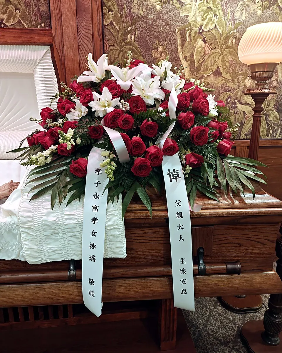 Red rose and white lily casket spray with ribbon streamers