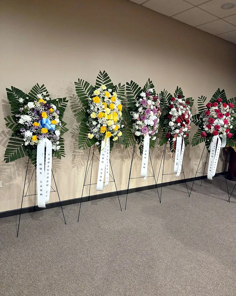 Pink, yellow, and white memorial wreath with lilies and roses
