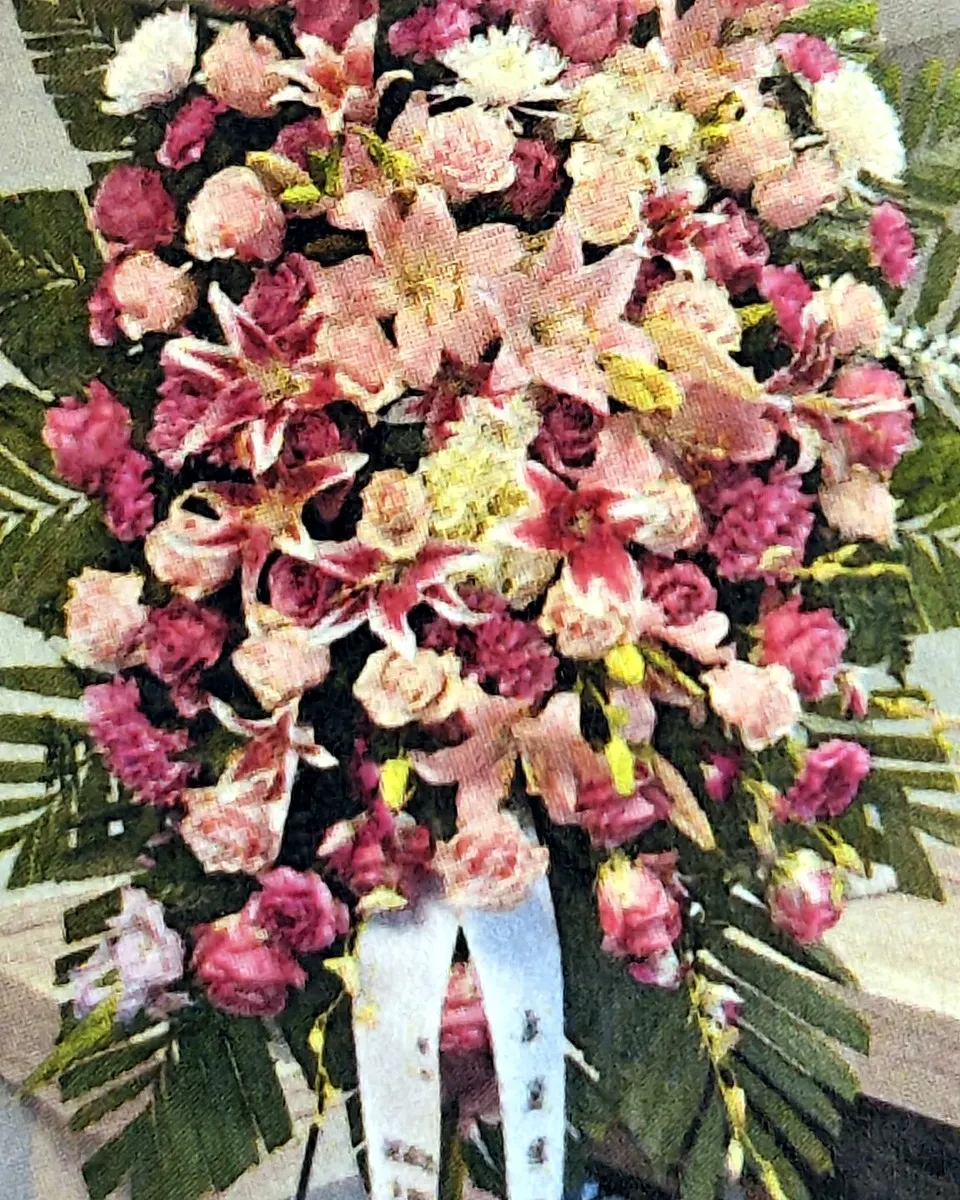 Pink standing funeral spray with lilies, carnations, and tropical foliage