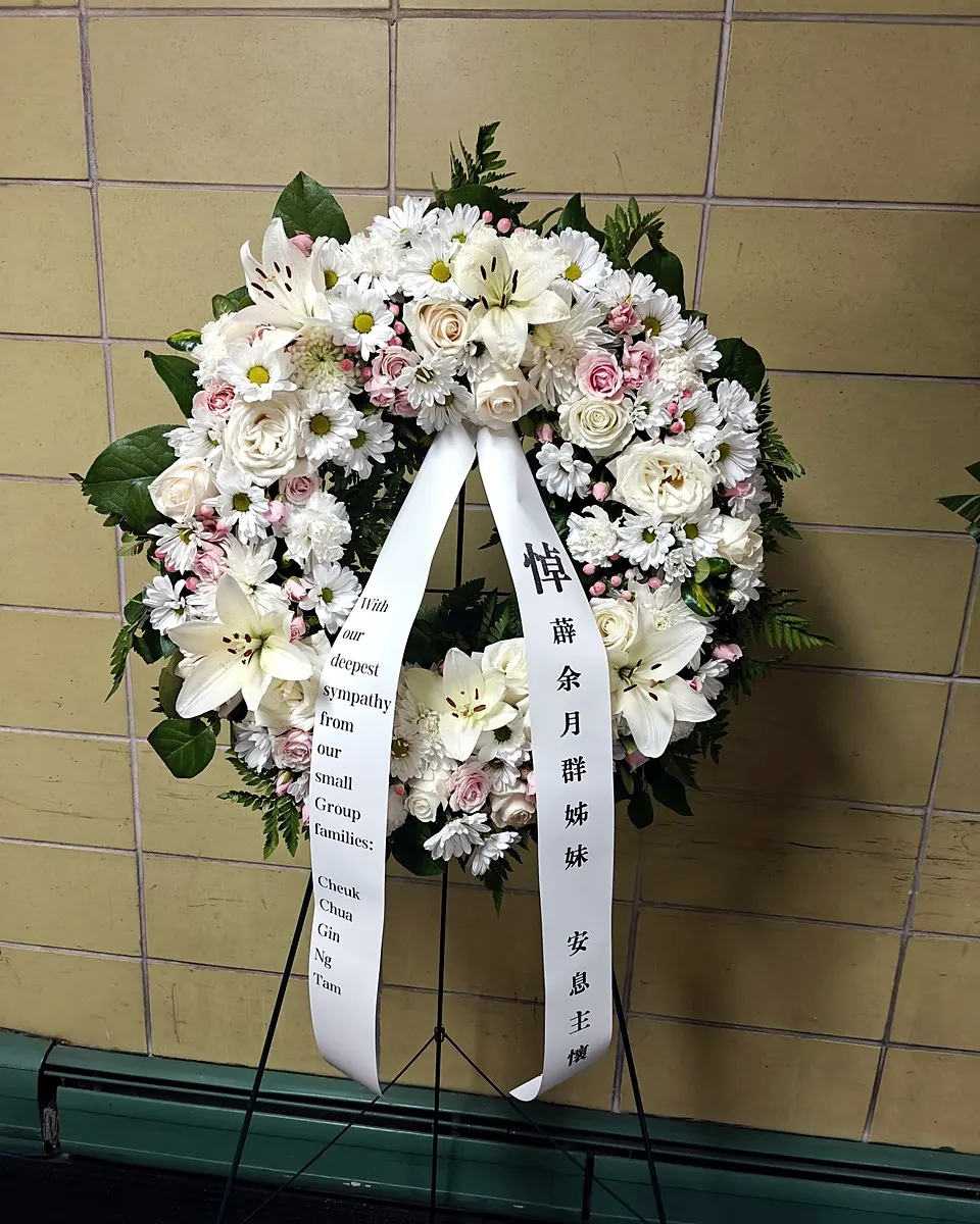 White and pale pink memorial wreath with roses, lilies, and chrysanthemums