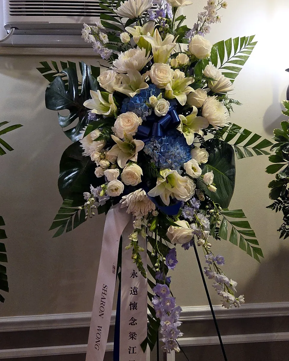 White and blue standing sympathy arrangement with lilies and roses