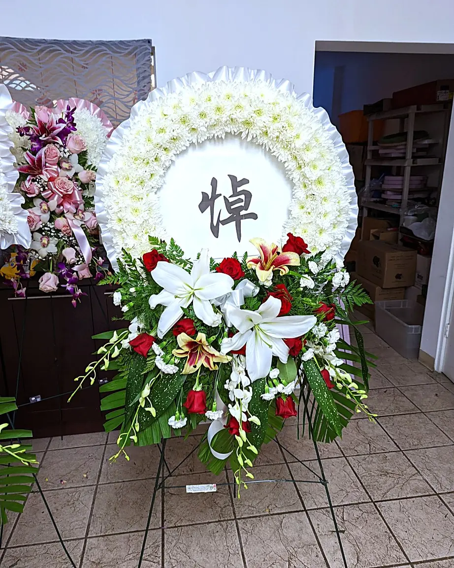 White chrysanthemum funeral wreath with red roses and white lilies