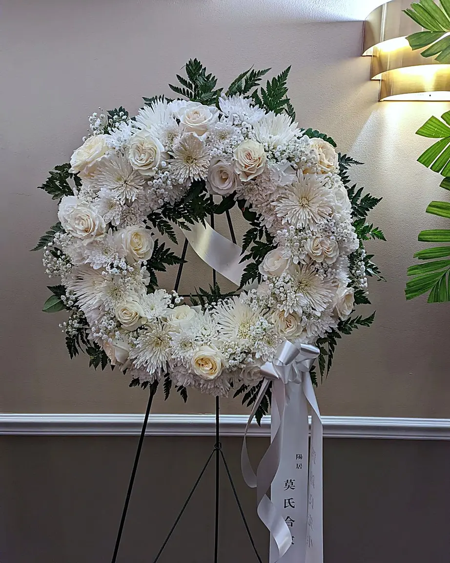 All-white funeral wreath with roses, spider mums, and baby's breath