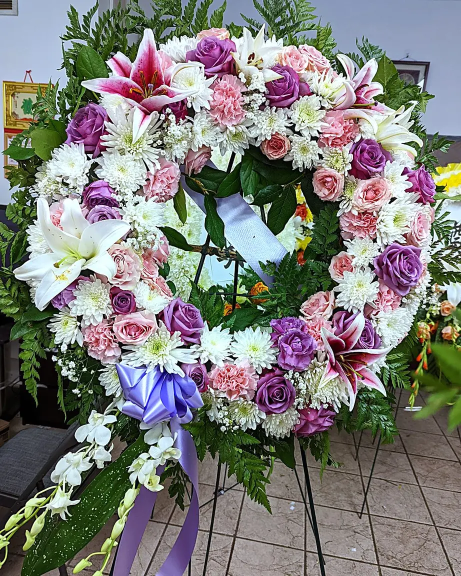 Funeral wreath with lavender and pink roses, lilies, and white chrysanthemums