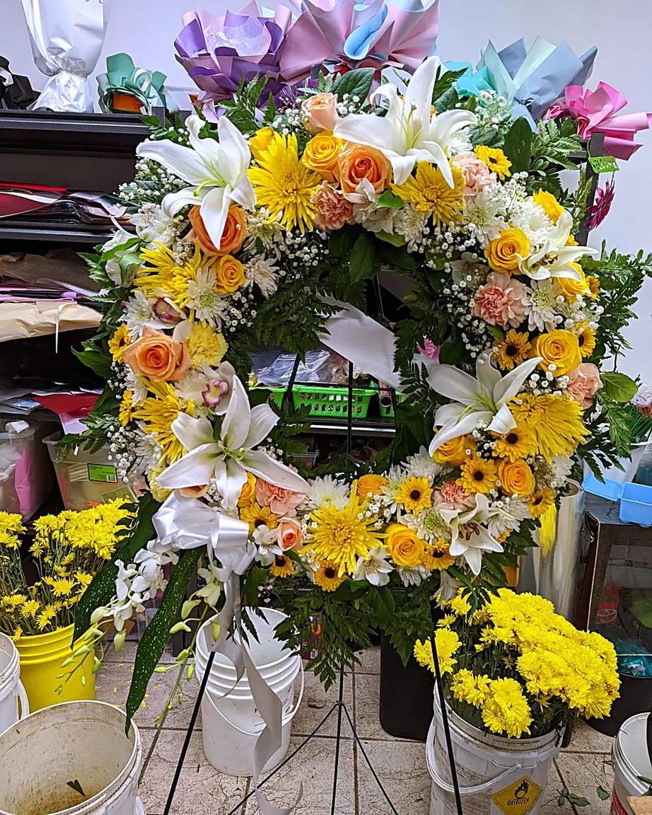 Funeral wreath with yellow chrysanthemums, peach roses, and white lilies